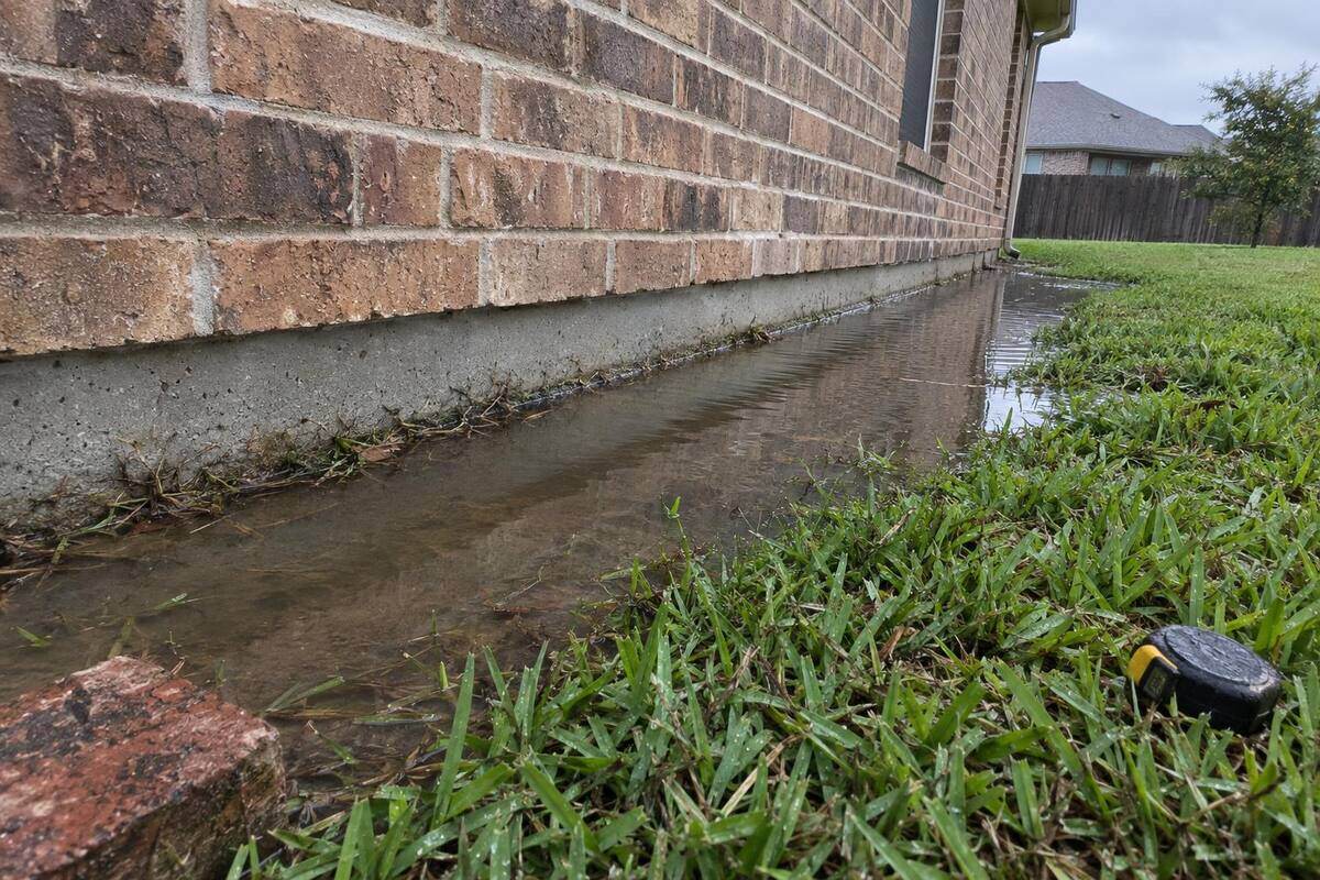 Rainwater standing in a strip along the exposed concrete edge of a slab below brick veneer